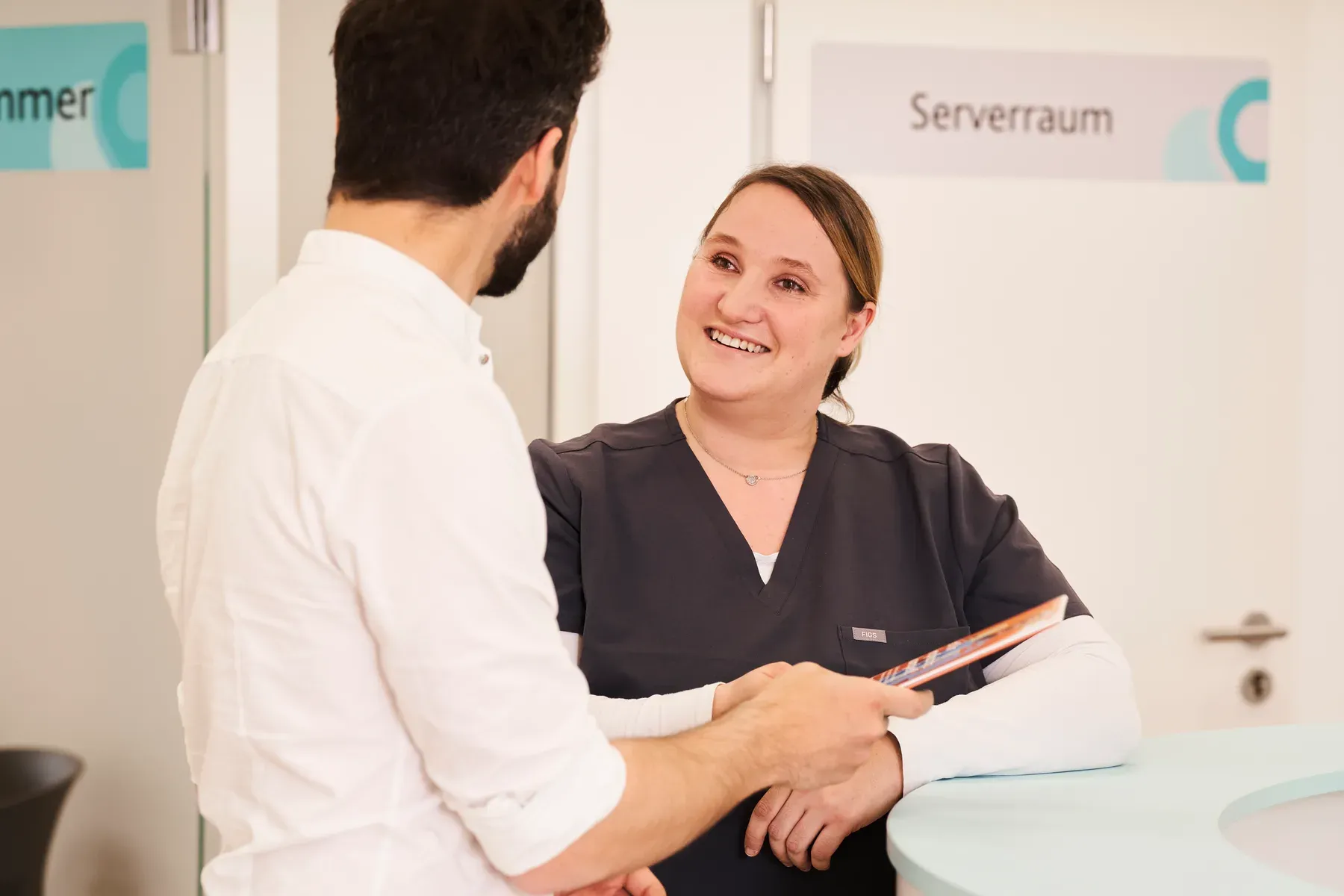 Zwei Mitarbeitende von Lillian Care im Gespräch am Empfang einer Praxis